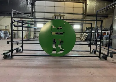 Black powder-coated metal gate with a green circular custom logo panel