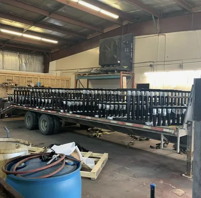 Large batch of black powder-coated fabricated assemblies loaded on a trailer
