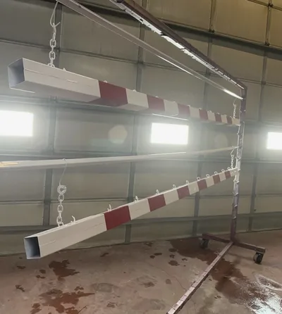 Red and white powder-coated barrier arms hanging in the shop