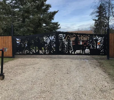 Wide black powder-coated driveway gate with wildlife and forest cutout artwork