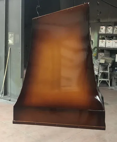 Large fabricated metal hood with a warm bronze or copper-toned finish