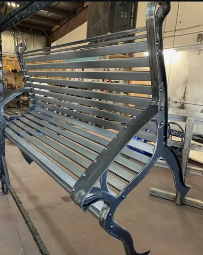 Finished park bench with black supports and clean metallic slats after refinishing