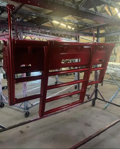 Large maroon powder-coated fabricated guard assembly hanging in the shop