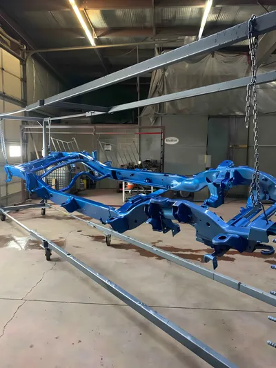 Large bright blue coated vehicle chassis hanging in the Clark's shop