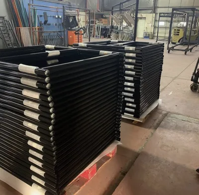 Stacks of black powder-coated tubular frames after finishing