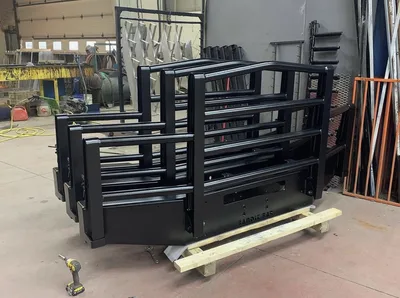 Black powder-coated heavy-duty guard assembly photographed with related shop work behind it