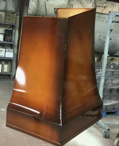 Tall fabricated metal hood with warm bronze or copper-toned powder-coated finish